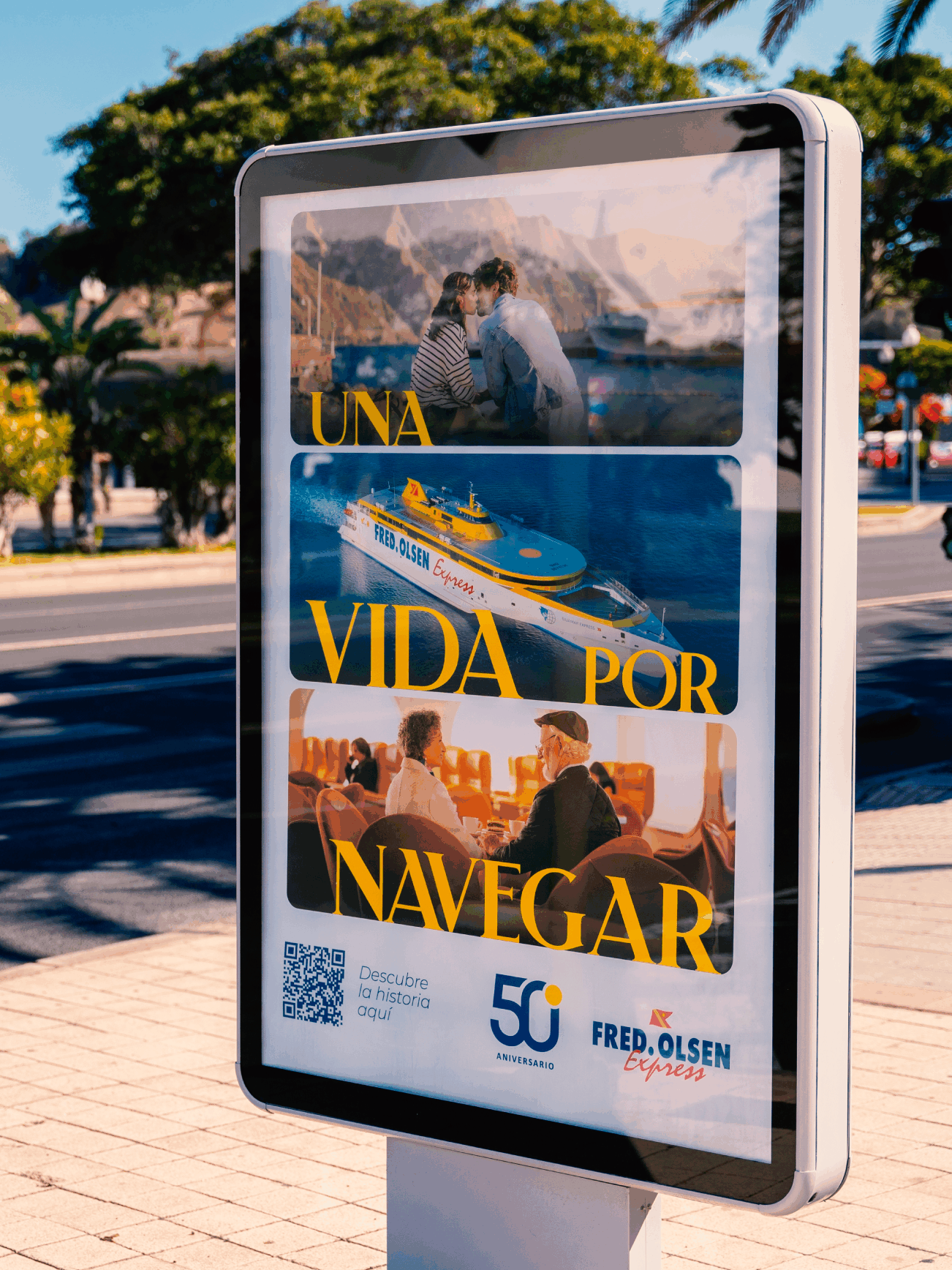 Mupi en la acera de una calle en un día soleado